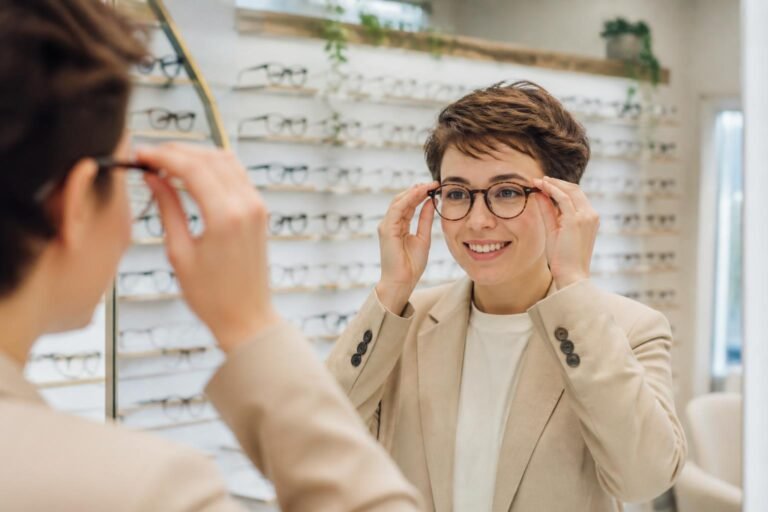 Femme essayant des lunettes à monture marron chez un opticien, avec présentoir de montures en arrière-plan