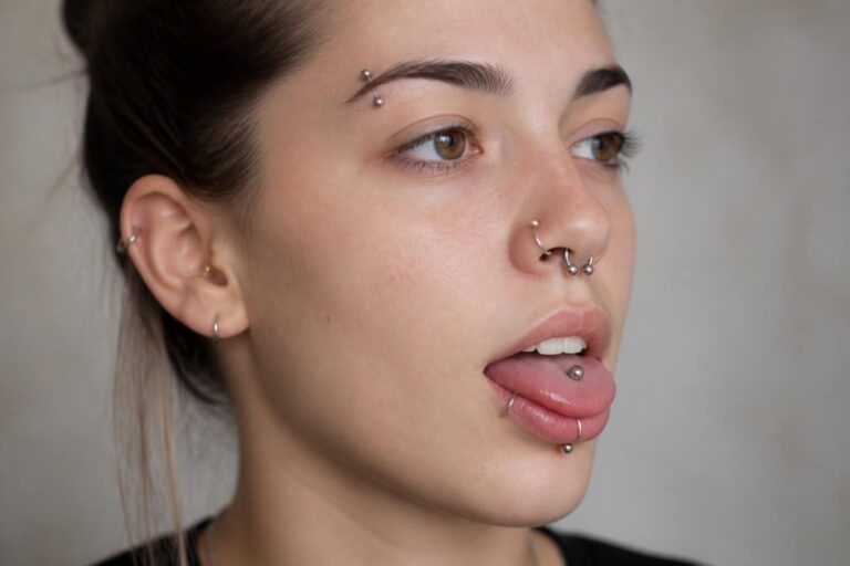 Visage avec piercings au nez, à la langue et au sourcil